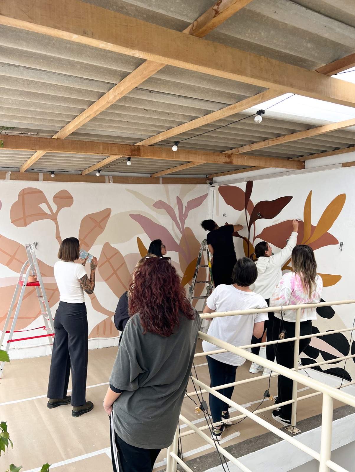 Participantes pintando um mural na Oficina Arte de Parede com Marcela no Netas